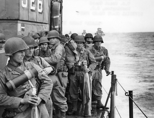 Photo of American soldiers onboard a ship approaching the coast of Normandy.